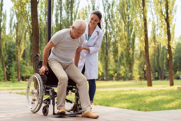 Happy old man tries to get up from the wheelchair and go