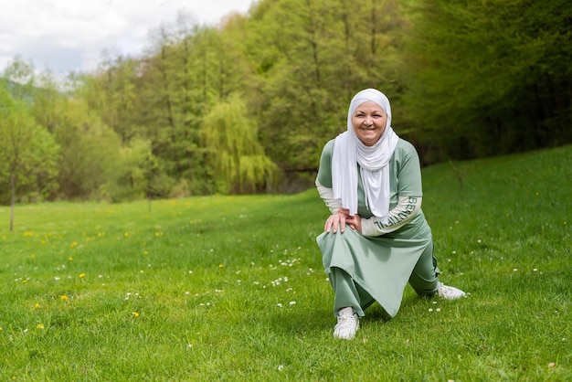 A happy old Muslim woman in hijab exercises in a summer park Healthy lifestyle wellbeing