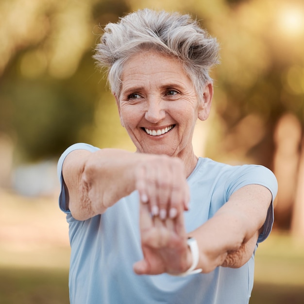 Happy old woman stretching in nature in fitness training body exercise or workout for wellness balance Smile relaxing or face of healthy senior person exercising in a calm peaceful park in spring