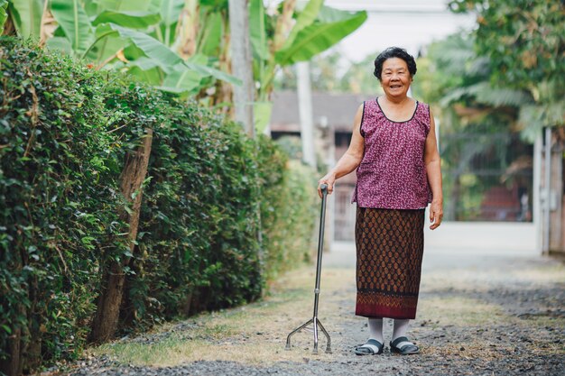 写真 幸せな古い祖母は杖で歩きます。