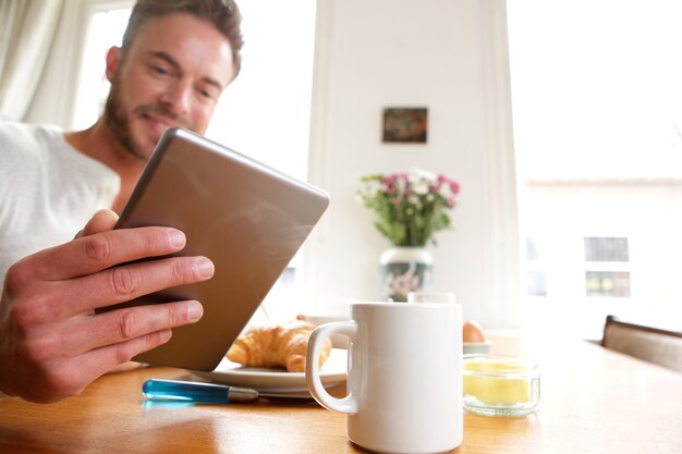 Uomo più anziano felice con la compressa sana della tenuta della prima colazione