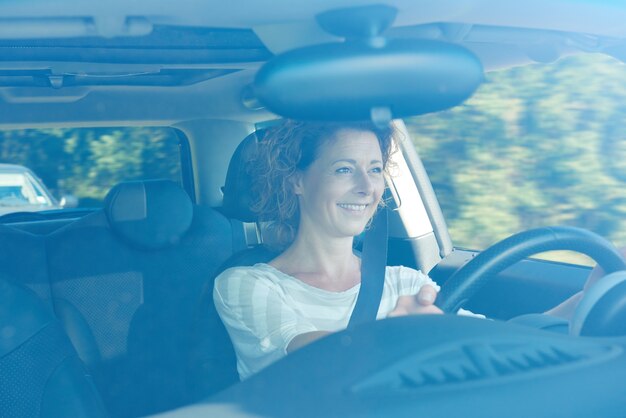 Felice donna anziana in auto in viaggio