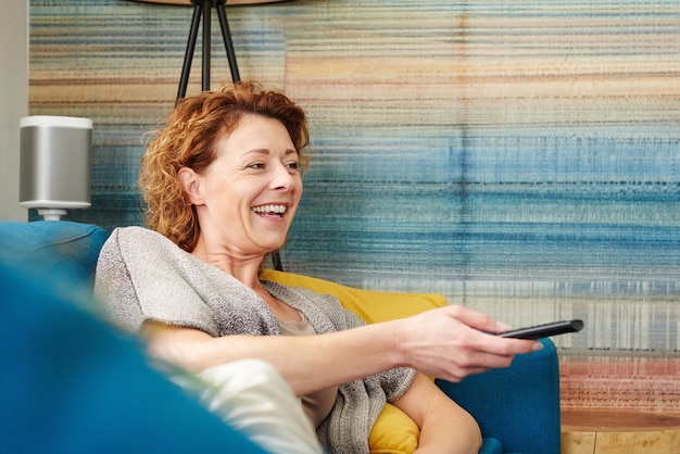 Photo happy older woman changing channel on television