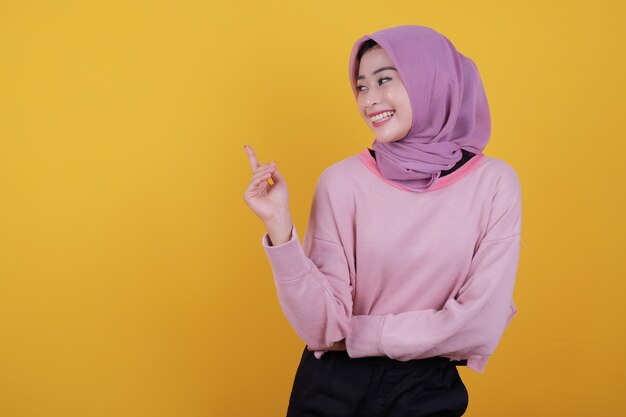 Happy overjoyed beautiful woman pointing something wearing soft pink T shirt