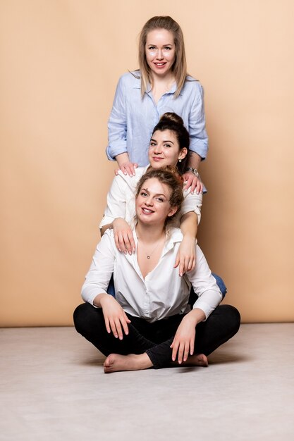 Photo happy and overweight multicultural women in bras isolated on beige. diverse beauty. three multiethnic ladies wrapped in bath towels posing smiling at camera on beige background. studio shot