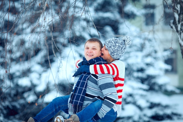 Happy pair of male and female embracing and having fun wearing warm clothes outside