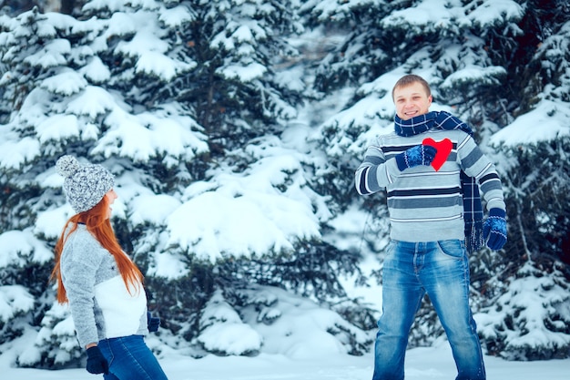 Happy pair of male and female embracing and having fun wearing warm clothes outside