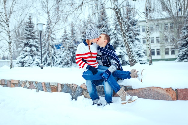 Happy pair of male and female embracing and having fun wearing warm clothes outside