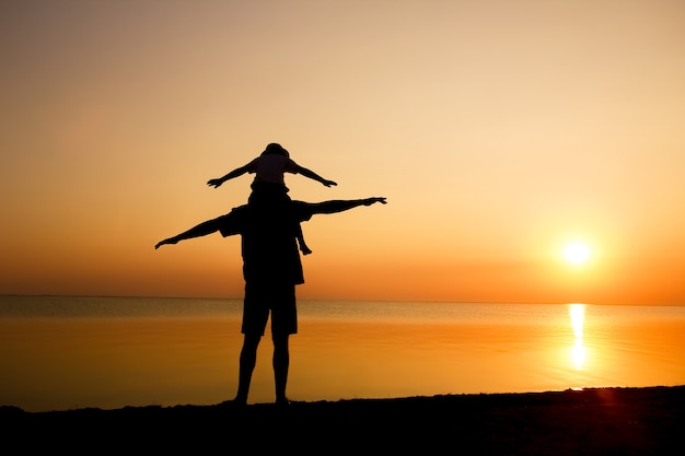 A happy parent with child by the sea play on nature silhouette travel