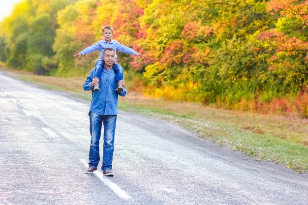 A Happy parent with a child in the park hands on nature travel go along the road