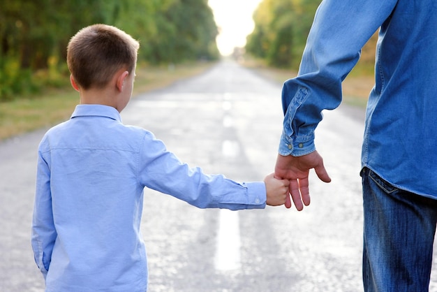 A Happy parent with a child in the park hands on nature travel go along the road