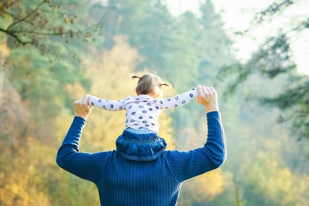 A Happy parent with a child in the park hands on nature travel go along the road