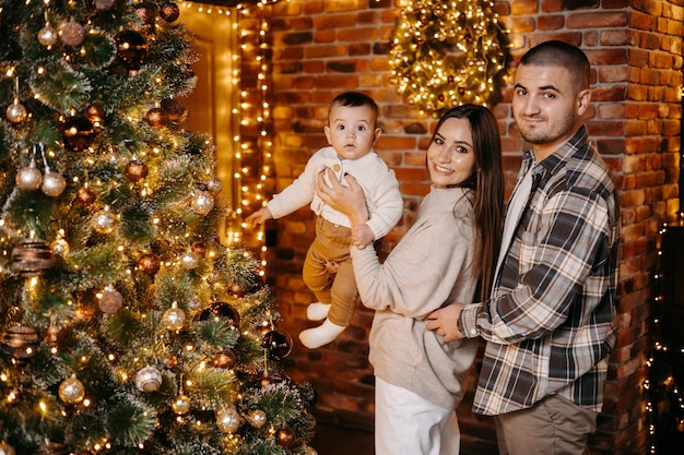 Happy parents celebrate Christmas with their beloved son in a beautiful cozy atmosphere at home.