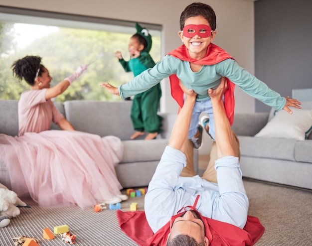 Счастливые родители и дети в костюмах играют вместе и веселятся вместе в гостиной Счастье взволновано, и семья наслаждается фантазийными нарядами для развлечения на Хэллоуин с детьми дома