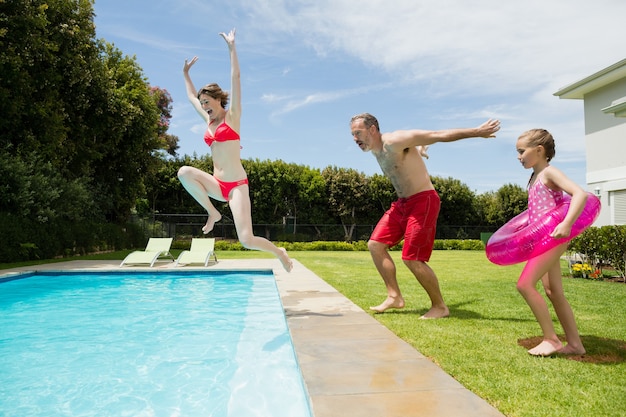 Happy parents and daughter jumping in swimming pool