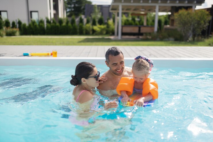 Photo happy parents. happy good-looking parents feeling unbelievable swimming in pool with daughter