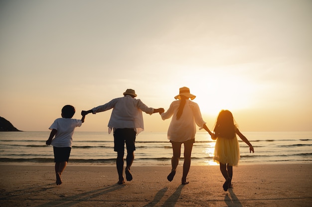 Happy parents and kid having fun with playing sand in summer vacation on the beachTravel