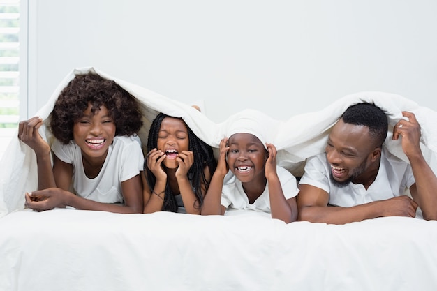 Happy parents and kids lying on bed