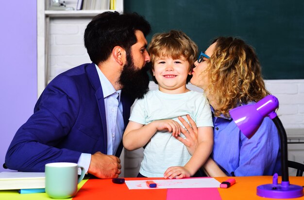 Happy parents kissing little son. Family schooling together. Children education. Parenting.