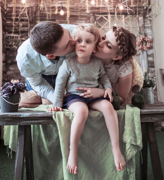 Счастливые родители целуют свою пятилетнюю дочь