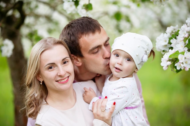 Happy parents mom and dad daughter young family outdoors in spring