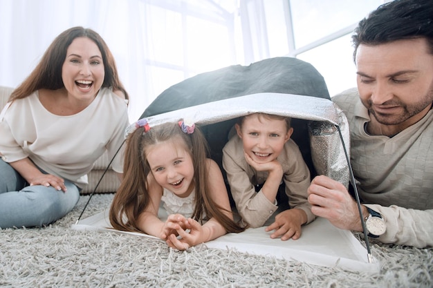 Happy parents play with children in a tent in the living room the concept of education
