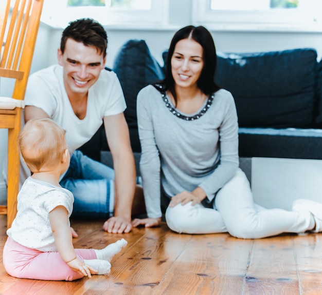 Photo happy parents playing with baby girl at home