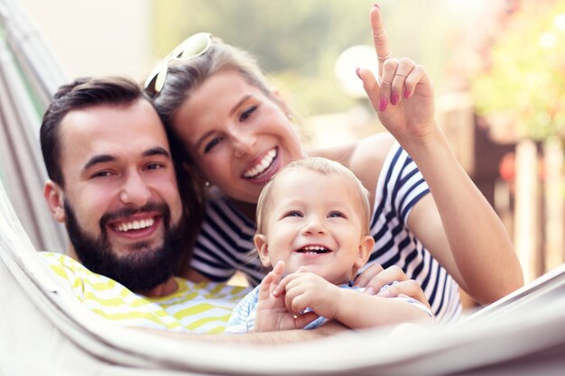 Happy parents playing with their baby boy in hammock outside