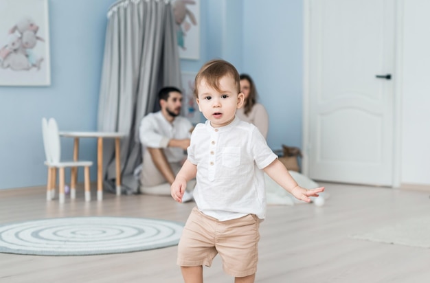 Happy parents relaxing on couch in comfort light living room while little kid child son playing on floor family having fun together