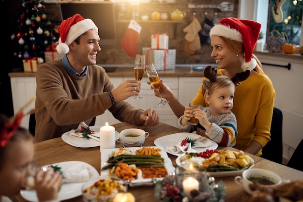 크리스마스에 가족 점심 시간에 샴페인과 함께 건배하는 행복한 부모