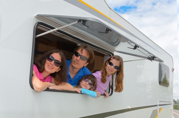 Happy parents traveling with kids and having fun in motorhome