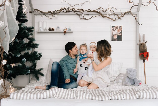 Happy parents with baby in decorated room for Christmas