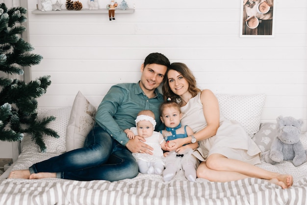 Happy parents with baby in decorated room for Christmas