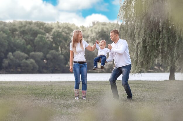 Счастливые родители с маленьким сыном вместе гуляют в весеннем парке