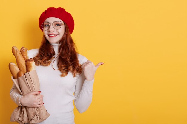 Foto la donna parigina felice con il sorriso positivo indica da parte