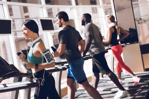 Happy people are running on a treadmill in the gym.