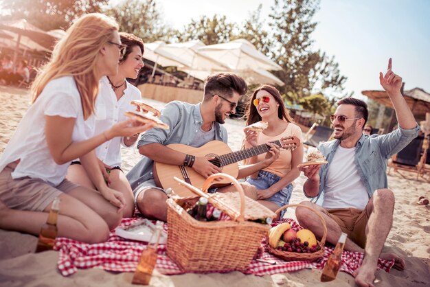 Happy people eating pizza and have fun on the beach