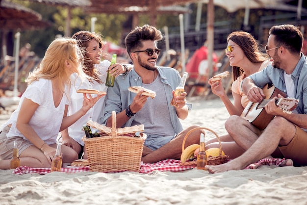 Happy people eating pizza and have fun on the beach