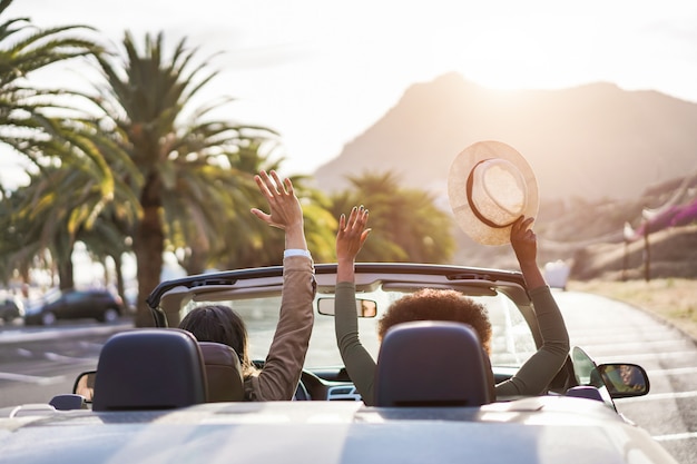 Gente felice divertirsi in auto convertibile in vacanza estiva al tramonto