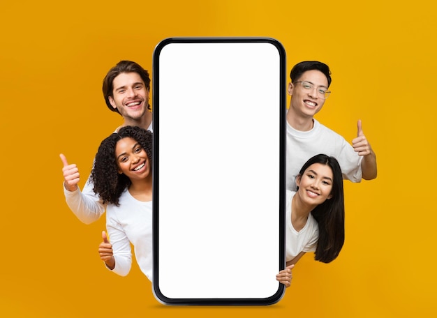 大きな空白のスマートフォンの後ろを覗いて親指を立てる幸せな人々
