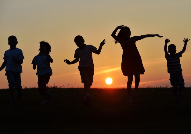 Foto sagome di persone felici in natura al momento del tramonto