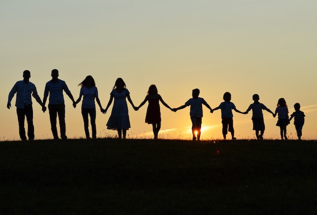 Happy people silhouettes outdoors on field