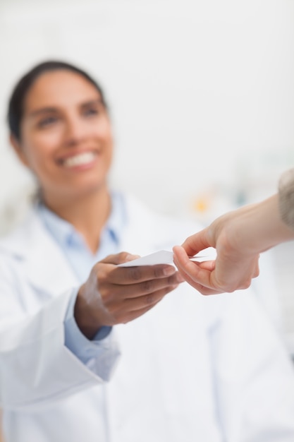 Happy pharmacist handing paper to a customer