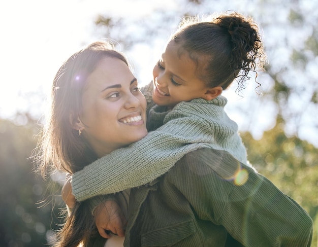 Photo happy piggyback and a mother and child in a park for playing bonding and quality time smile hug and a young mom with a girl kid in nature with love care and happiness on mothers day together