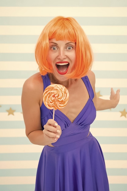 Happy pinup model with lollipop in hand Fashion girl with orange hair having fun Cool girl with lollipop Sexy woman Crazy girl in playful mood Sweet look So much fun Going crazy Enjoy party