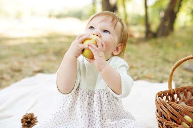 Photo happy playful child outdoors in autumn park eating apple