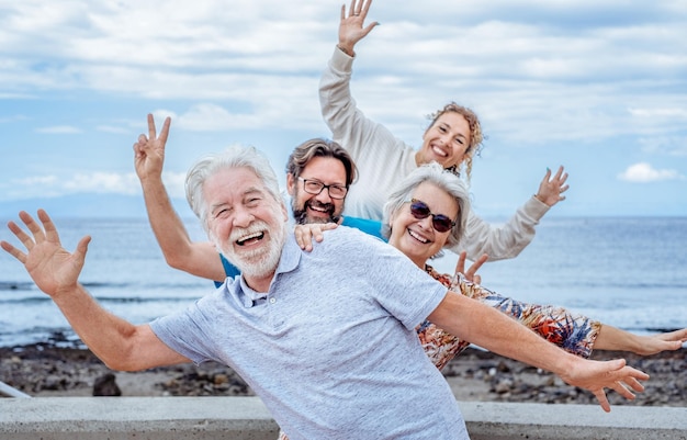 Happy playful multigenerational family group outdoors at seaside expressing joy gesturing with hand