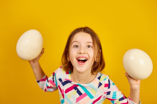 Happy playful teenager girl holding Ostrich eggs