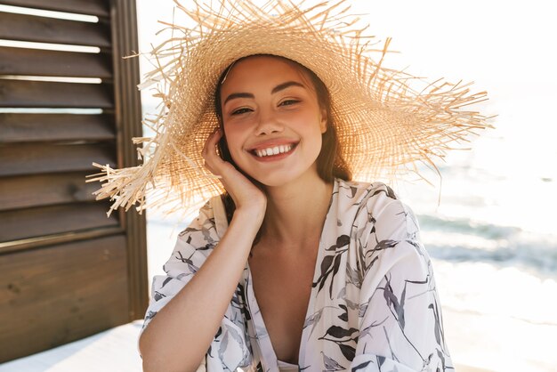  happy pleased smiling young beautiful woman at the beach posing in hat.