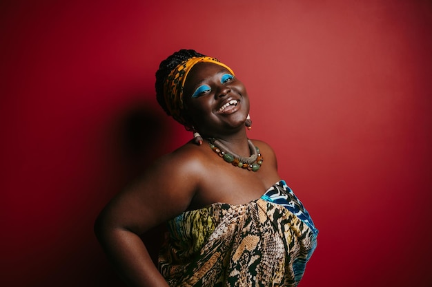 Счастливая африканская женщина с красивым макияжем в традиционных головных уборах на красном фоне
